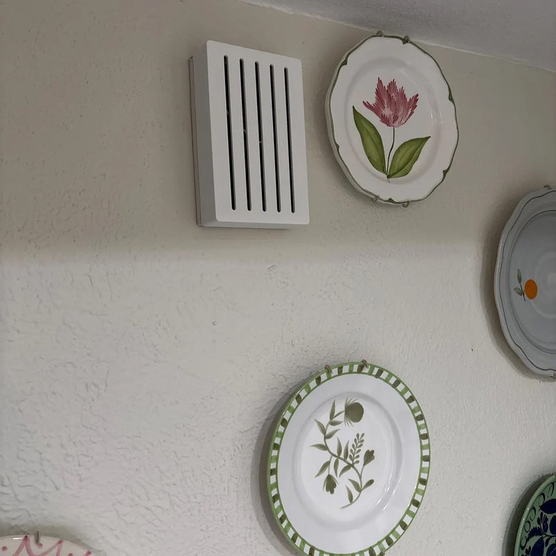 White Louver chime cover on a wall next to decorative floral plates