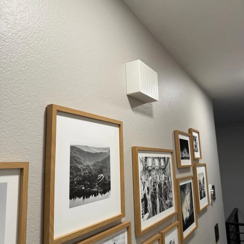 White chime cover with vertical slots above a gallery wall of framed photos